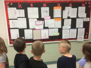 Students check out our mastery wall of writing while waiting for lunch. Teacher teams selected exemplary pieces of work at the mid-year point.